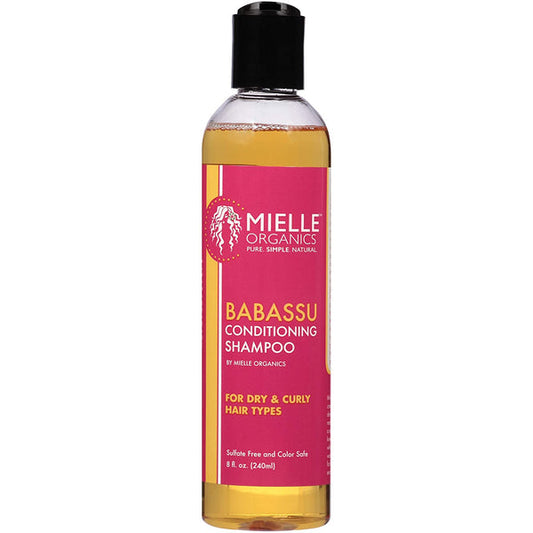 A bottle of Mielle Organics Babassu Conditioning Shampoo with a black cap and a pink label, containing golden-yellow liquid, shown on a white background.